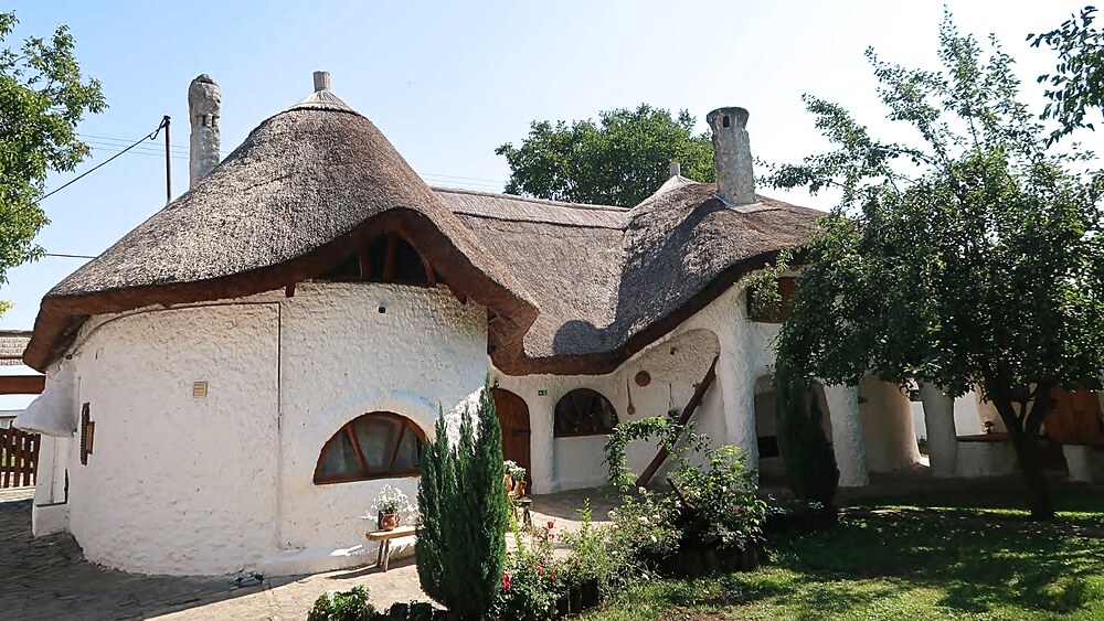 A Yeyo Udvarház egyik nádtetős háza kívülről, kertben